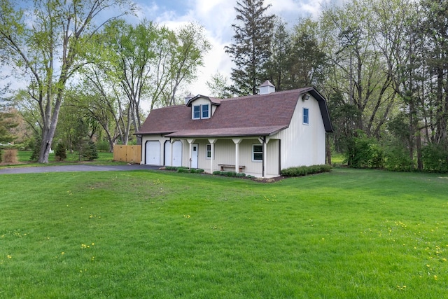 view of front of property featuring driveway, a chimney, roof with shingles, a front lawn, and an attached garage