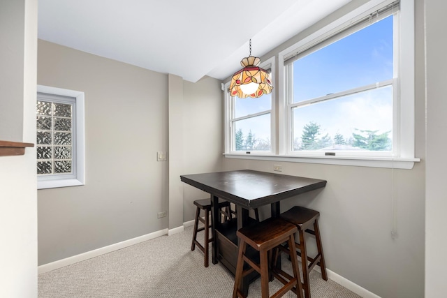 dining room with baseboards, a wealth of natural light, and light carpet