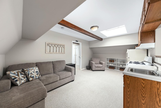 carpeted living area featuring a skylight, baseboards, beamed ceiling, and a sink