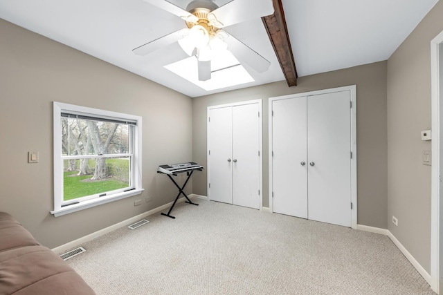 bedroom with a skylight, multiple closets, beamed ceiling, and visible vents