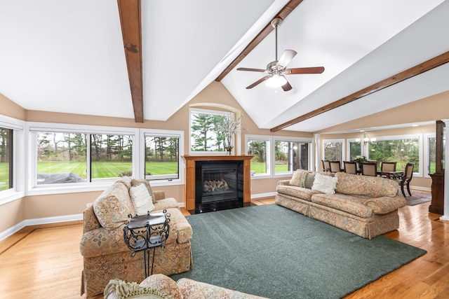 living room featuring ceiling fan, baseboards, a fireplace with flush hearth, vaulted ceiling with beams, and wood finished floors