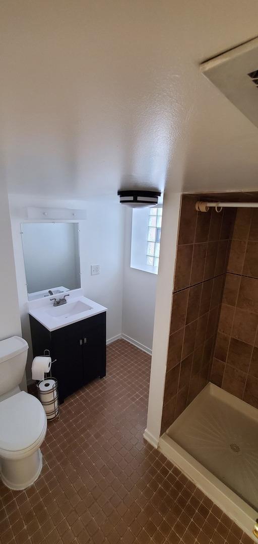 4627 W Schubert Ave, Chicago, IL 60639 - bathroom featuring baseboards, toilet, a stall shower, and vanity