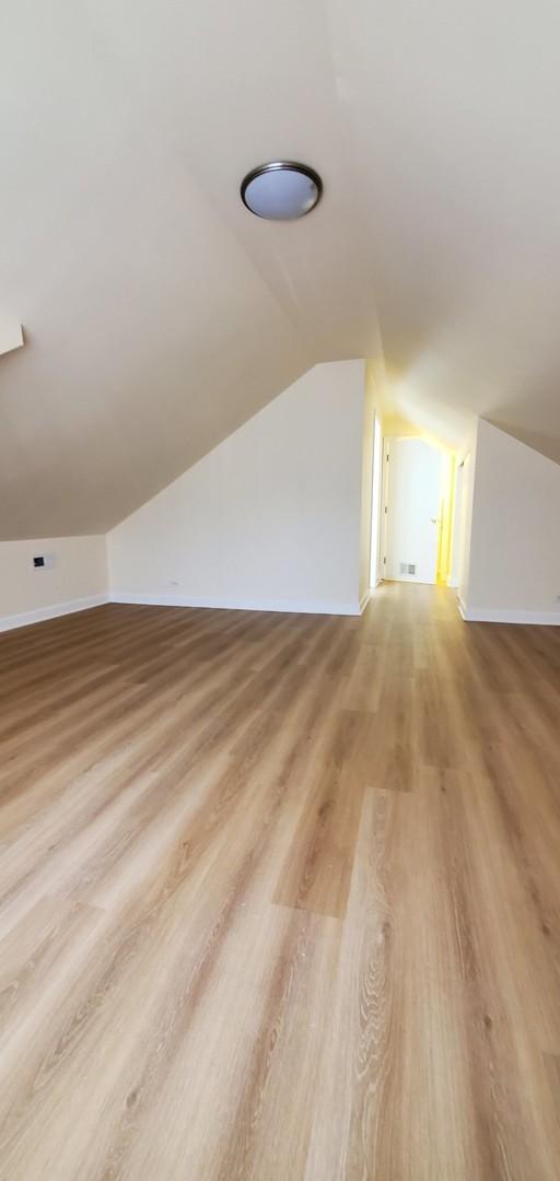 4627 W Schubert Ave, Chicago, IL 60639 - additional living space with visible vents, baseboards, lofted ceiling, and wood finished floors
