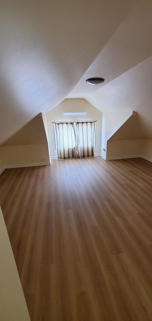 4627 W Schubert Ave, Chicago, IL 60639 - additional living space featuring baseboards, vaulted ceiling, and wood finished floors
