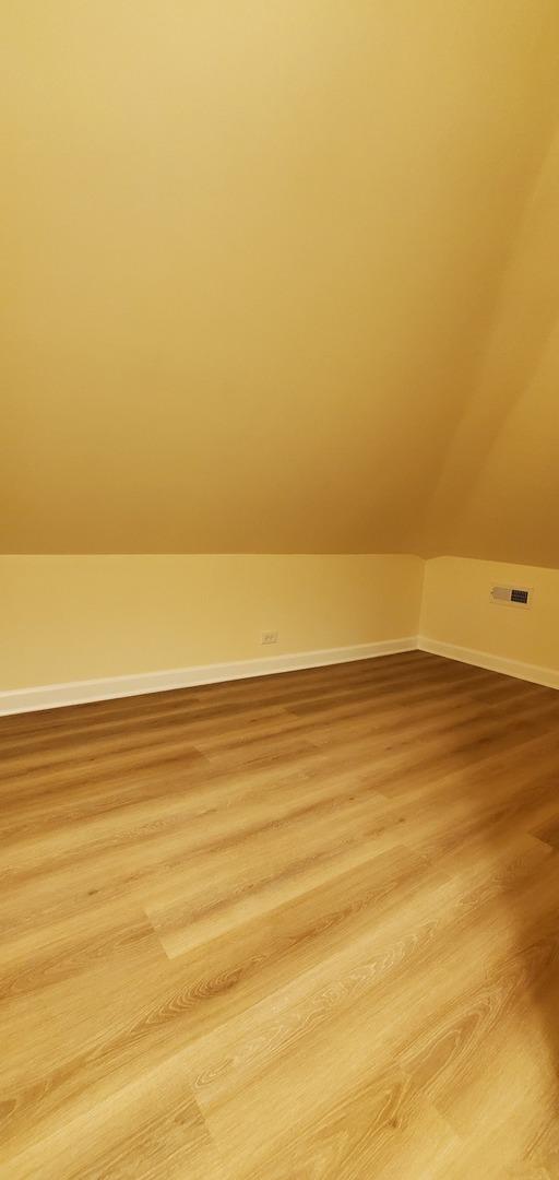 4627 W Schubert Ave, Chicago, IL 60639 - bonus room featuring baseboards, lofted ceiling, visible vents, and light wood-style flooring