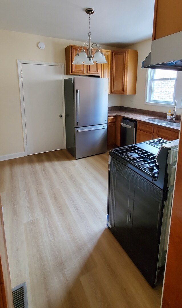 4627 W Schubert Ave, Chicago, IL 60639 - kitchen featuring ventilation hood, brown cabinets, stainless steel appliances, and an inviting chandelier