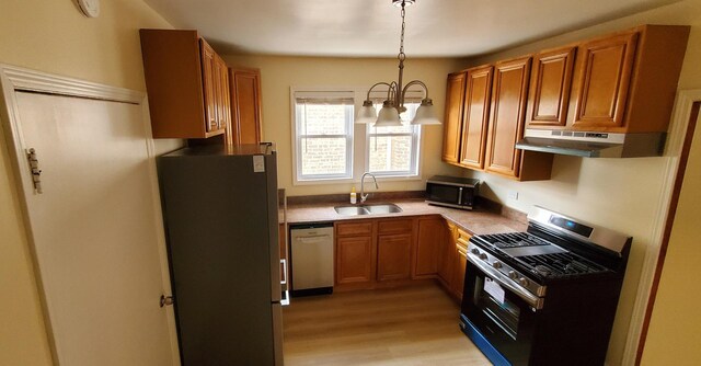 4627 W Schubert Ave, Chicago, IL 60639 - kitchen featuring appliances with stainless steel finishes, under cabinet range hood, a sink, decorative light fixtures, and brown cabinetry
