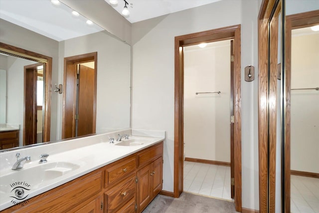 bathroom with baseboards, double vanity, and a sink