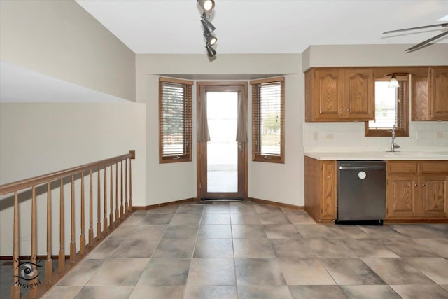 kitchen featuring rail lighting, brown cabinetry, light countertops, and dishwasher