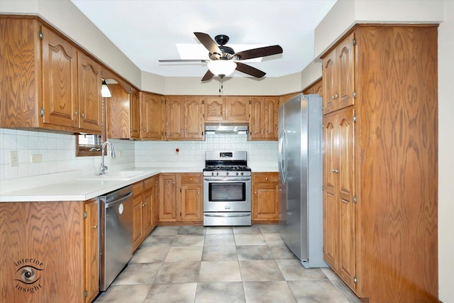 kitchen featuring brown cabinetry, stainless steel appliances, a sink, and a ceiling fan