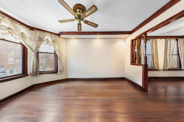 empty room with wood finished floors, ceiling fan, ornamental molding, and baseboards