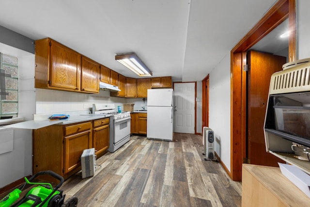 kitchen with brown cabinets, light countertops, under cabinet range hood, wood finished floors, and white appliances