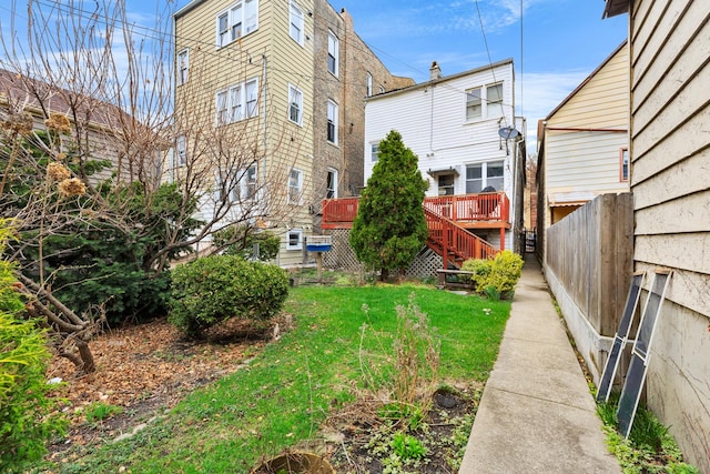 view of yard with fence, a wooden deck, and stairs