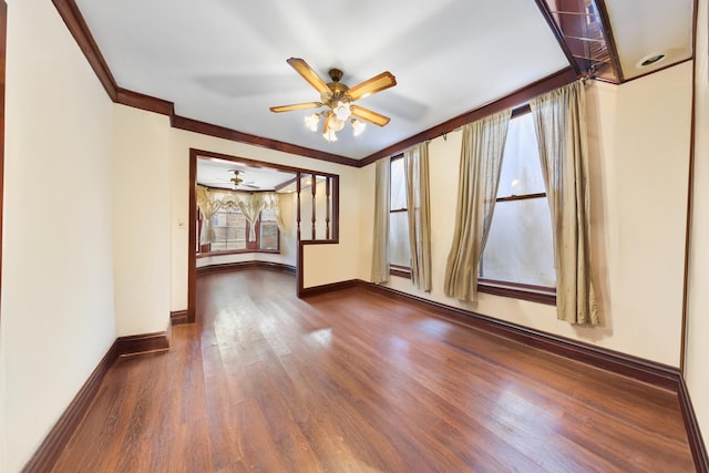 empty room with ornamental molding, a ceiling fan, wood finished floors, and baseboards