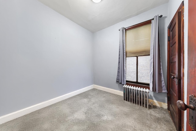 carpeted spare room with baseboards and radiator heating unit