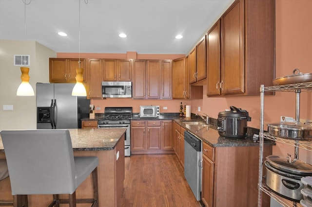 6510 S Woodlawn Ave Unit 1, Chicago, IL 60637 - kitchen featuring visible vents, wood finished floors, brown cabinets, appliances with stainless steel finishes, and a breakfast bar area
