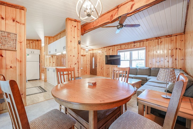 dining area featuring beam ceiling, wooden walls, and ceiling fan with notable chandelier