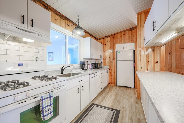 kitchen with light countertops, wooden walls, white appliances, under cabinet range hood, and lofted ceiling