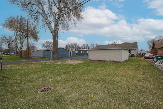 view of yard featuring aphalt driveway and an outdoor structure