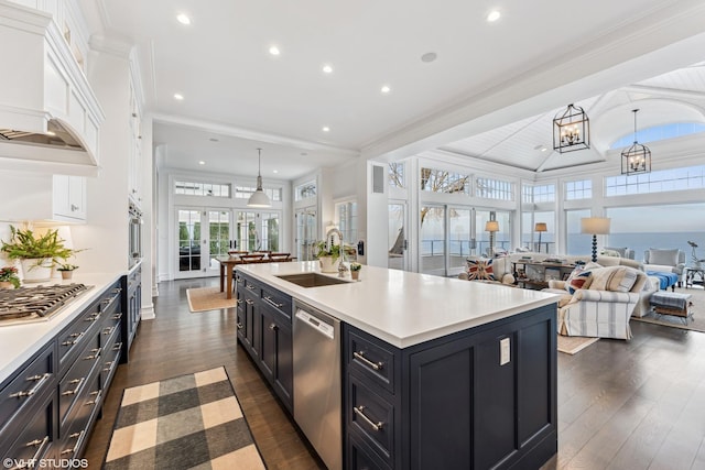 kitchen with a sink, stainless steel appliances, dark wood finished floors, light countertops, and open floor plan