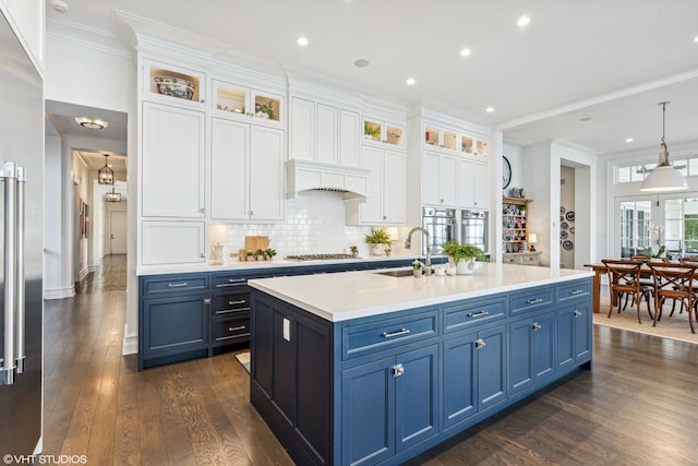 kitchen featuring blue cabinetry, a sink, stainless steel appliances, white cabinetry, and dark wood-style floors