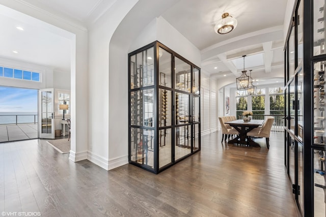 wine cellar featuring arched walkways, coffered ceiling, wood finished floors, baseboards, and beamed ceiling