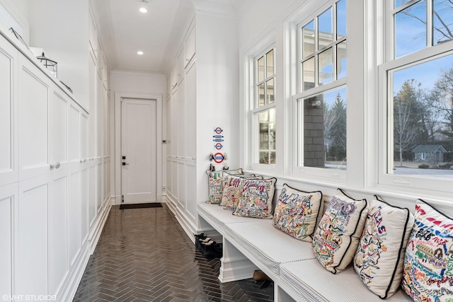 corridor with brick floors, crown molding, a decorative wall, and recessed lighting