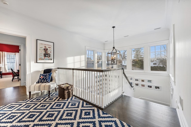 hall featuring an upstairs landing, a chandelier, wood finished floors, ornamental molding, and baseboards