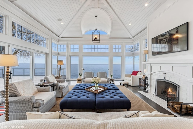 living area with high vaulted ceiling, wood finished floors, a fireplace, a chandelier, and wood ceiling