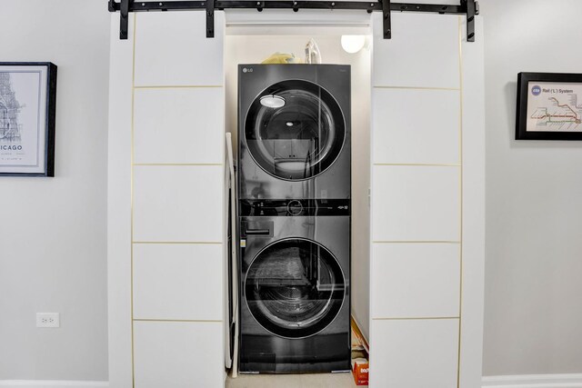 laundry area featuring stacked washer and dryer, a barn door, and laundry area