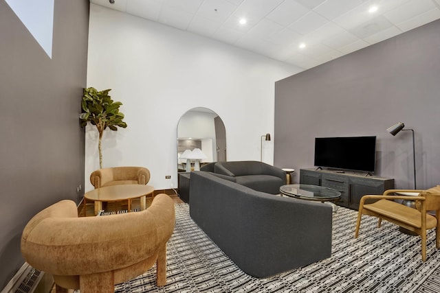 living room featuring arched walkways and a towering ceiling