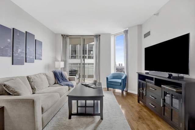 living room featuring light wood-style flooring, baseboards, and visible vents