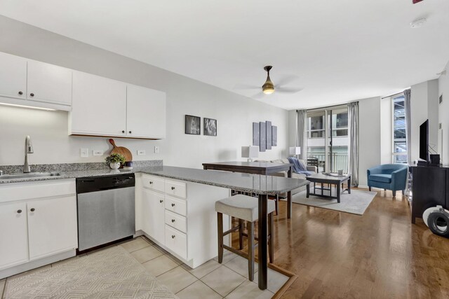 kitchen with dishwasher, a sink, open floor plan, ceiling fan, and a peninsula