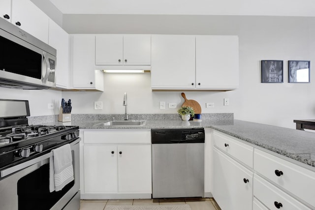 kitchen with white cabinetry, light stone counters, light tile patterned flooring, a sink, and stainless steel appliances