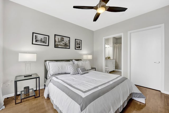 bedroom featuring baseboards, a ceiling fan, ensuite bath, and wood finished floors