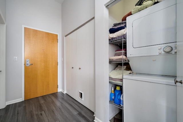 laundry room featuring baseboards, stacked washer / drying machine, wood finished floors, and laundry area