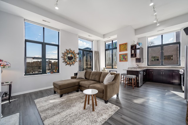 living area featuring track lighting, baseboards, dark wood-type flooring, and visible vents
