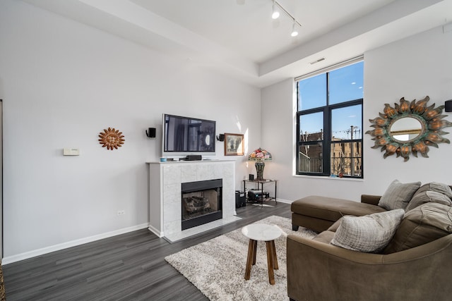 living room with visible vents, a tiled fireplace, rail lighting, baseboards, and dark wood-style floors