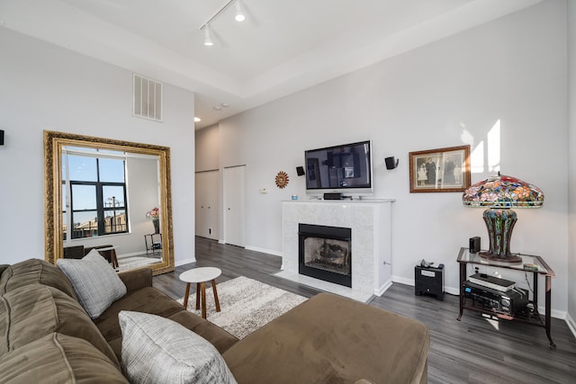 living area with baseboards, visible vents, track lighting, and dark wood-type flooring