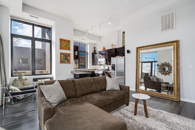 living area featuring a healthy amount of sunlight, dark wood-style flooring, rail lighting, and visible vents