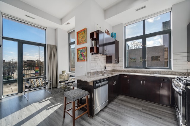 kitchen featuring visible vents, light stone counters, a sink, appliances with stainless steel finishes, and a wealth of natural light