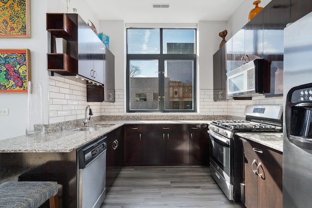 kitchen with visible vents, open shelves, a sink, light wood finished floors, and stainless steel appliances