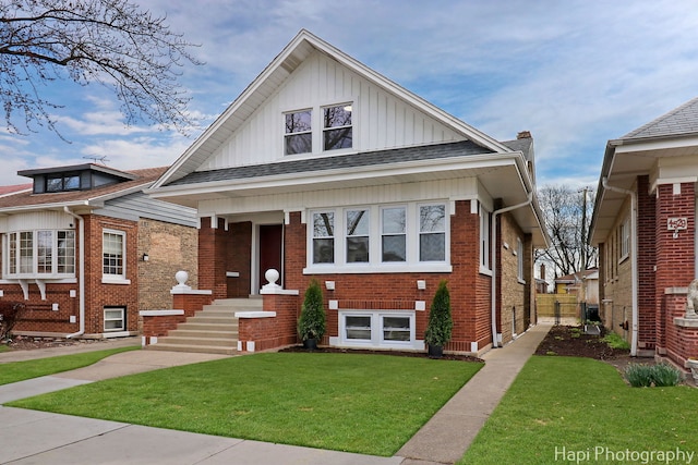bungalow featuring a front lawn, brick siding, roof with shingles, and board and batten siding