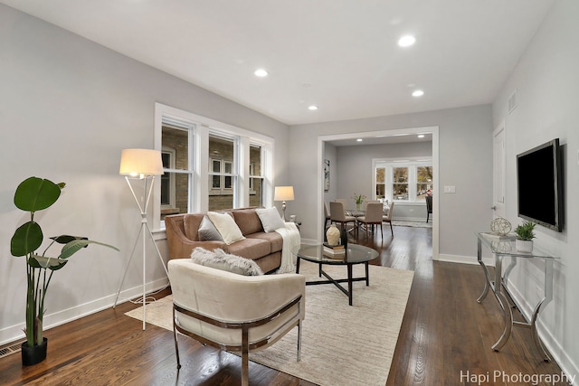 living area with dark wood-type flooring, visible vents, baseboards, and recessed lighting