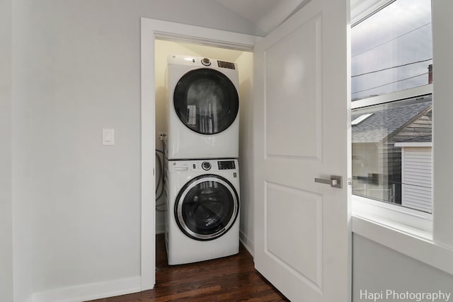 laundry area with stacked washer / drying machine, baseboards, laundry area, and dark wood-style flooring