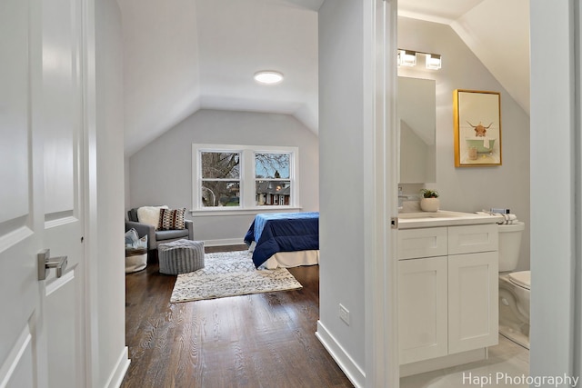 bathroom featuring vaulted ceiling, toilet, vanity, and wood finished floors