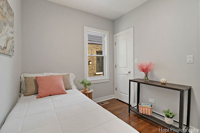 bedroom with baseboards, wood finished floors, and visible vents