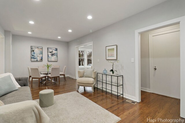 living room featuring baseboards, visible vents, recessed lighting, and dark wood finished floors