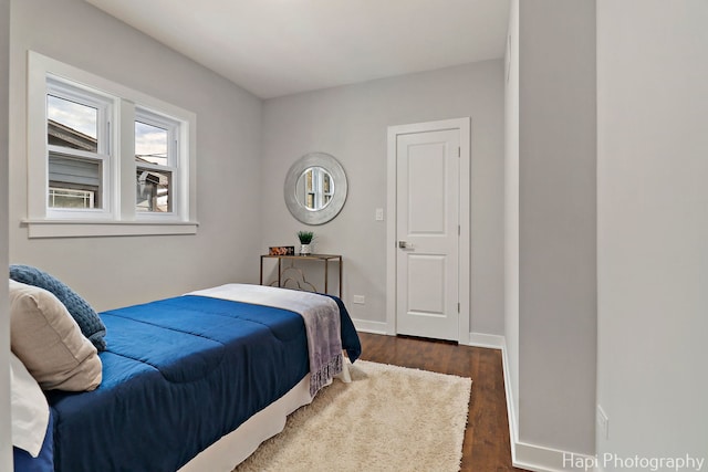 bedroom featuring baseboards, wood finished floors, and multiple windows