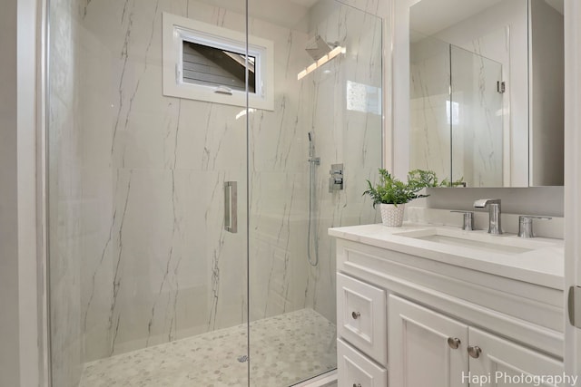 full bath featuring a marble finish shower and vanity